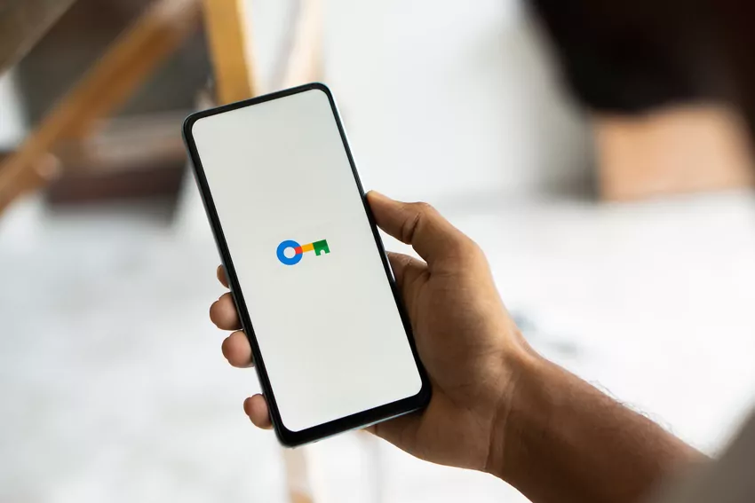 Mężczyzna trzyma w dłoni smartfon z zapewniającym bezpieczeństwo danych menedżerem haseł połączonym z kontem Google.